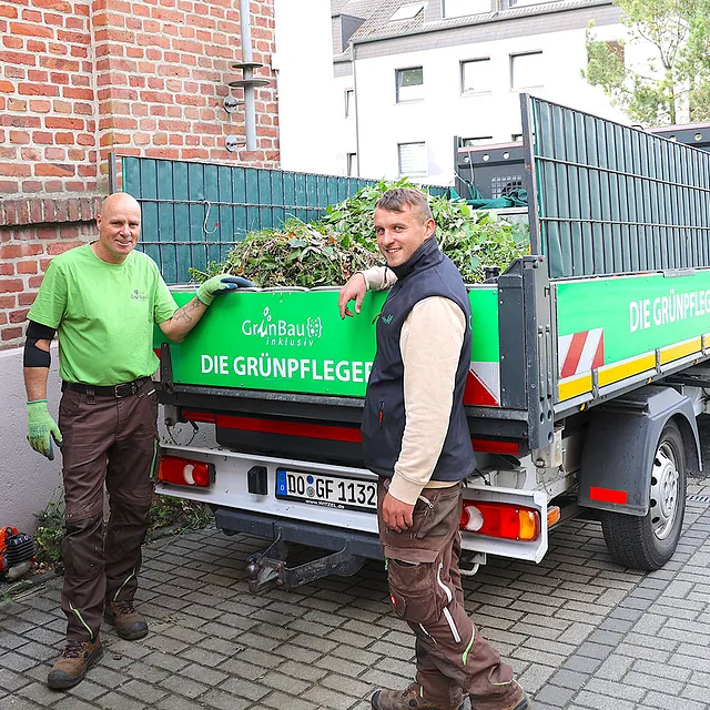 Mitarbeiter von GrünBau inklusiv nach Gartenpflegearbeiten am Fahrzeug