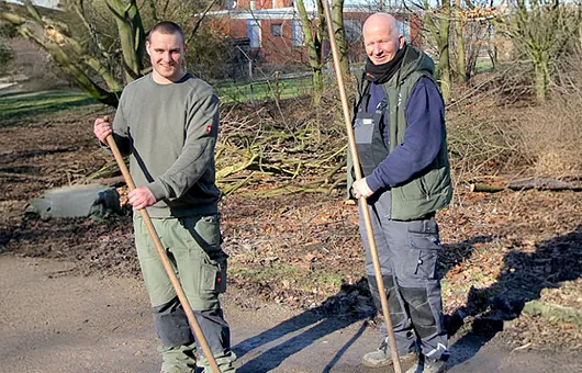 Zwei Mitarbeiter bei Pflegearbeiten an Grünflächen und Gehölzen